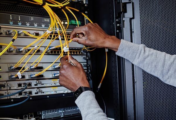 Close up of IT engineer connecting cables in server room while setting up data network, copy space